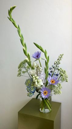 a vase filled with flowers sitting on top of a green table next to a white wall