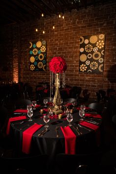 a black table cloth with red flowers and candles on it in front of two wall paintings