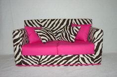 a zebra print couch with pink pillows on it's arm and backrests