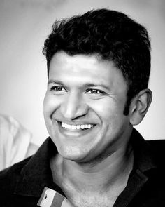 a black and white photo of a man with short hair smiling at the camera,