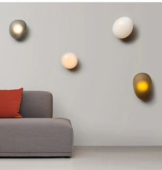 a couch sitting in front of a white wall with three lights on it's side