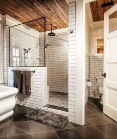 a bathroom with a white toilet sitting next to a walk in shower and a wooden ceiling