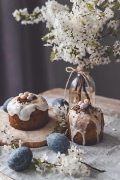 two bundt cakes sitting on top of a wooden table next to flowers and rocks