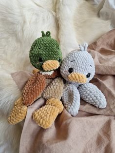 two knitted stuffed animals sitting on top of a bed next to eachother