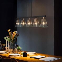 a dining room table with place settings and flowers in vases on the top shelf