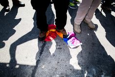 the shadow of people standing in front of a colorful bag on the ground with other people behind them