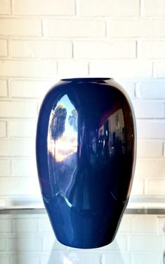 a blue vase sitting on top of a glass table next to a white brick wall