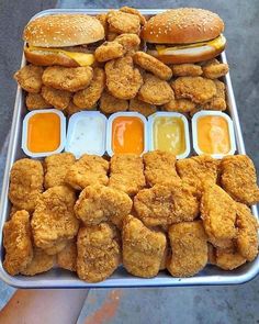 chicken nuggies and cheeseburgers are arranged on a tray with dipping sauces