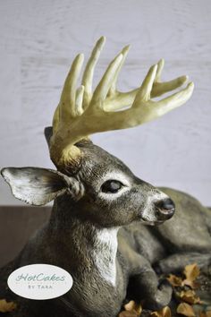 a statue of a deer with antlers on it's head sitting in leaves