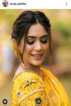 a woman in yellow sari smiling and looking at the camera with her eyes closed