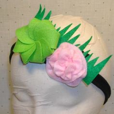 a white mannequin head with green leaves and pink flower