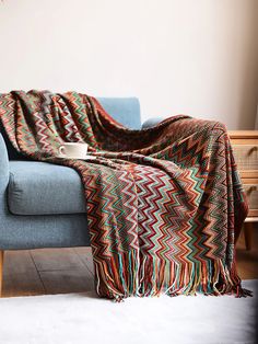 a couch with a blanket on top of it and a coffee cup in the middle