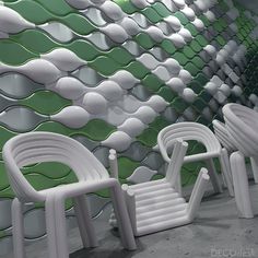 several white chairs are lined up in front of a green wall with wavy shapes on it