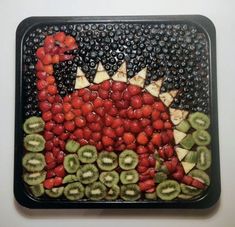 a tray filled with fruit shaped like a dinosaur