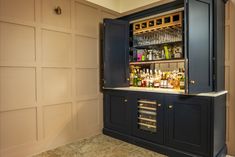 the bar is built into the wall and has liquor bottles on it's shelves