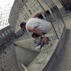 a man riding a skateboard up the side of a cement wall next to a fence