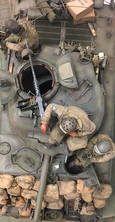 a man in uniform is working on an army tank with many other items around him