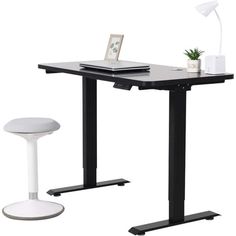 a black and white computer desk with a laptop on it, next to a stool