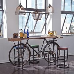 two bicycles are parked in front of a table with bottles on it and three stools