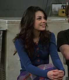 a man and woman sitting next to each other in front of a stove top oven