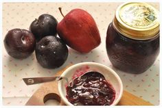 plums, pears and jam are sitting on a table with a wooden spoon