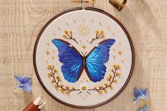 a blue butterfly with yellow flowers on it's wings is shown in the hoop