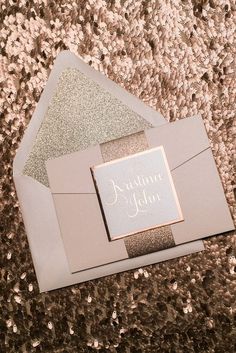 the wedding card is laying on top of an envelope with gold foil and glitters