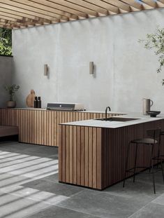 an outdoor kitchen is shown with wooden cabinets and counter tops, as well as stools