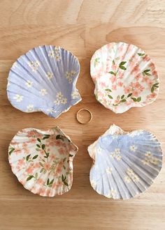 four seashells on a wooden surface with one ring in the middle and three other shells around them