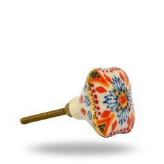 an orange and blue flowered glass knob on a gold plated brass screw head