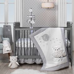 a baby crib with two stuffed animals on the floor next to it and a lamp