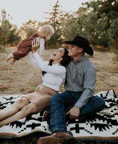 a man, woman and baby are sitting on a blanket