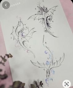 a drawing of a dragon on a sheet of paper next to some leaves and flowers