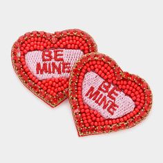 two red beaded heart shaped brooches with the words be mine on them