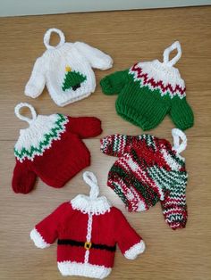 four knitted christmas sweaters and hats on a wooden table with white string hanging from the top