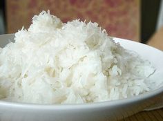 a white bowl filled with rice on top of a wooden table