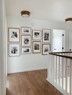 a hallway with pictures hanging on the wall and wooden flooring in front of it