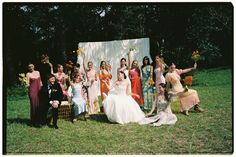 a group of people standing next to each other in front of a white wall with flowers on it