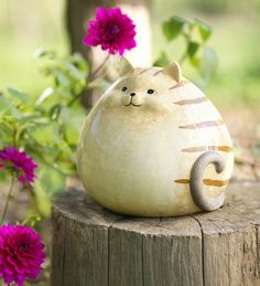 a ceramic cat sitting on top of a wooden stump