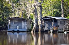 two houses on stilts in the middle of a flooded area with trees and water surrounding them