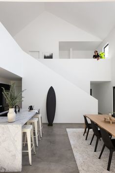 a dining room table with chairs and a surfboard on the wall next to it