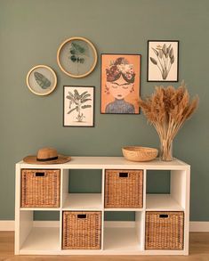 a white shelf with baskets and pictures on the wall