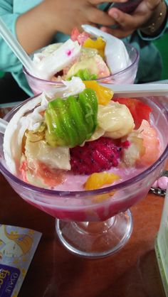 a bowl filled with fruit and ice cream on top of a table