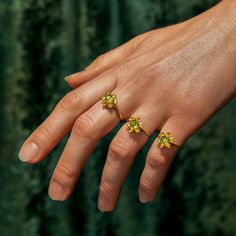 This delicate ring features an impressive, untreated Peridot at the center of its daffodil inspired setting. Inspired by the secret floral language of Victorian Europe, daffodils had many meanings depending on the context in which they were gifted. Victorians saw daffodils as symbols of chivalry and unrequited love. However, some myths and legends go down a darker path, with daffodils showing up as symbols of narcissism, numbness, and Hell itself. In modern times, daffodils are enduring symbols Green Flower Ring For Promise, Green Open Flower Ring For Promise, Buttercup Ring, Myths And Legends, Unrequited Love, Yellow Tones, Modern Times, Delicate Rings, Narcissism