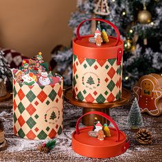 three christmas themed boxes sitting on top of a wooden table next to a christmas tree