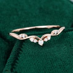 a gold ring with three diamonds sitting on top of green velvet material in front of a white background