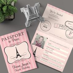 two pink passport cards with the eiffel tower in paris on them, next to a potted plant