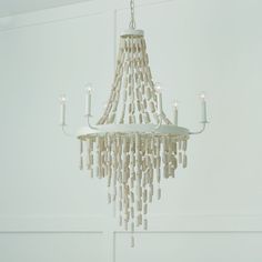 a white chandelier with candles hanging from it's sides in a room