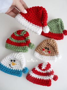 crocheted hats and mittens are arranged on a white surface with a hand holding one