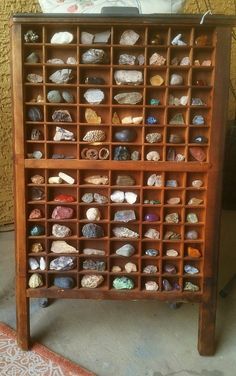 a wooden shelf with many different types of rocks on it and a magazine rack in the middle